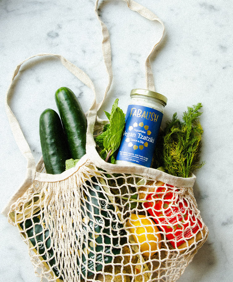 Eine Stofftasche mit buntem Gemüse und einem Glas Tzatziki