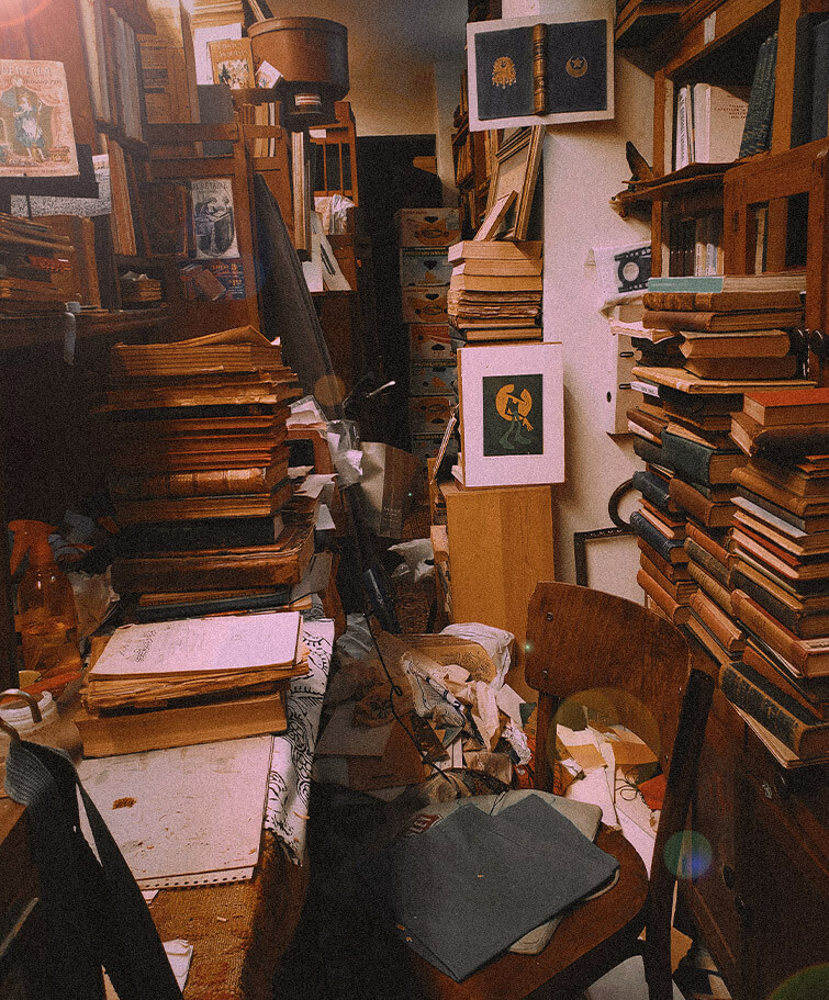 Das Foto zeigt einen unordentlichen Raum mit haufenweise Papier und ganz vielen Büchern